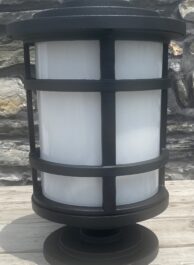 A light on wooden decking with a stone wall in the background