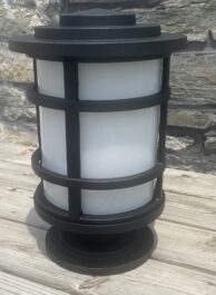 A light on wooden decking with a stone wall in the background
