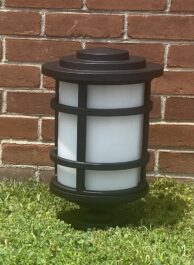A light on the grass with a wall in the background