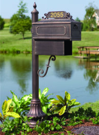 A brown mailbox with a lake in the background.