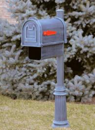 A blue mailbox with grass and a tree in the background.