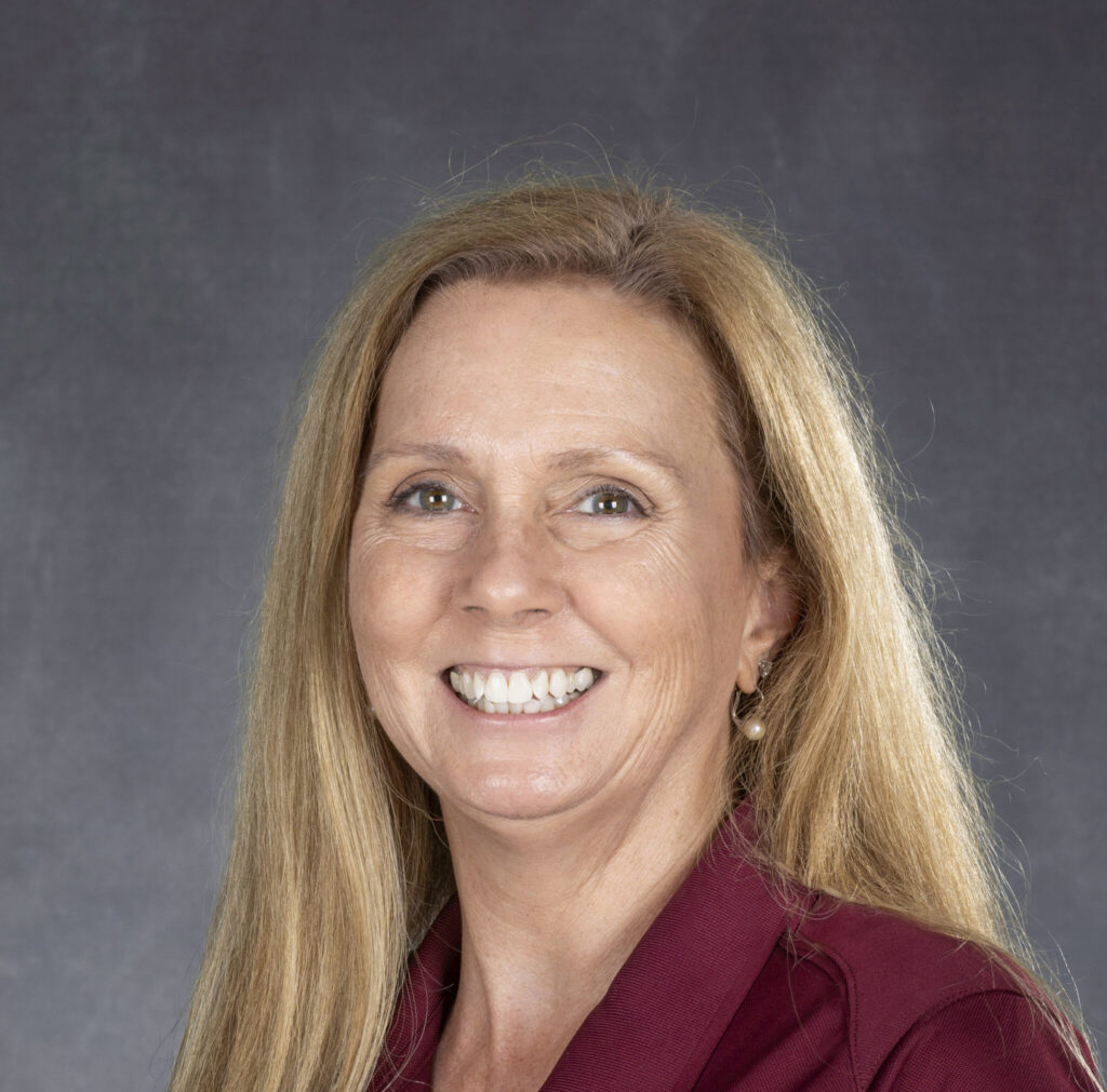A portrait image of a woman smiling with long blonde hair.